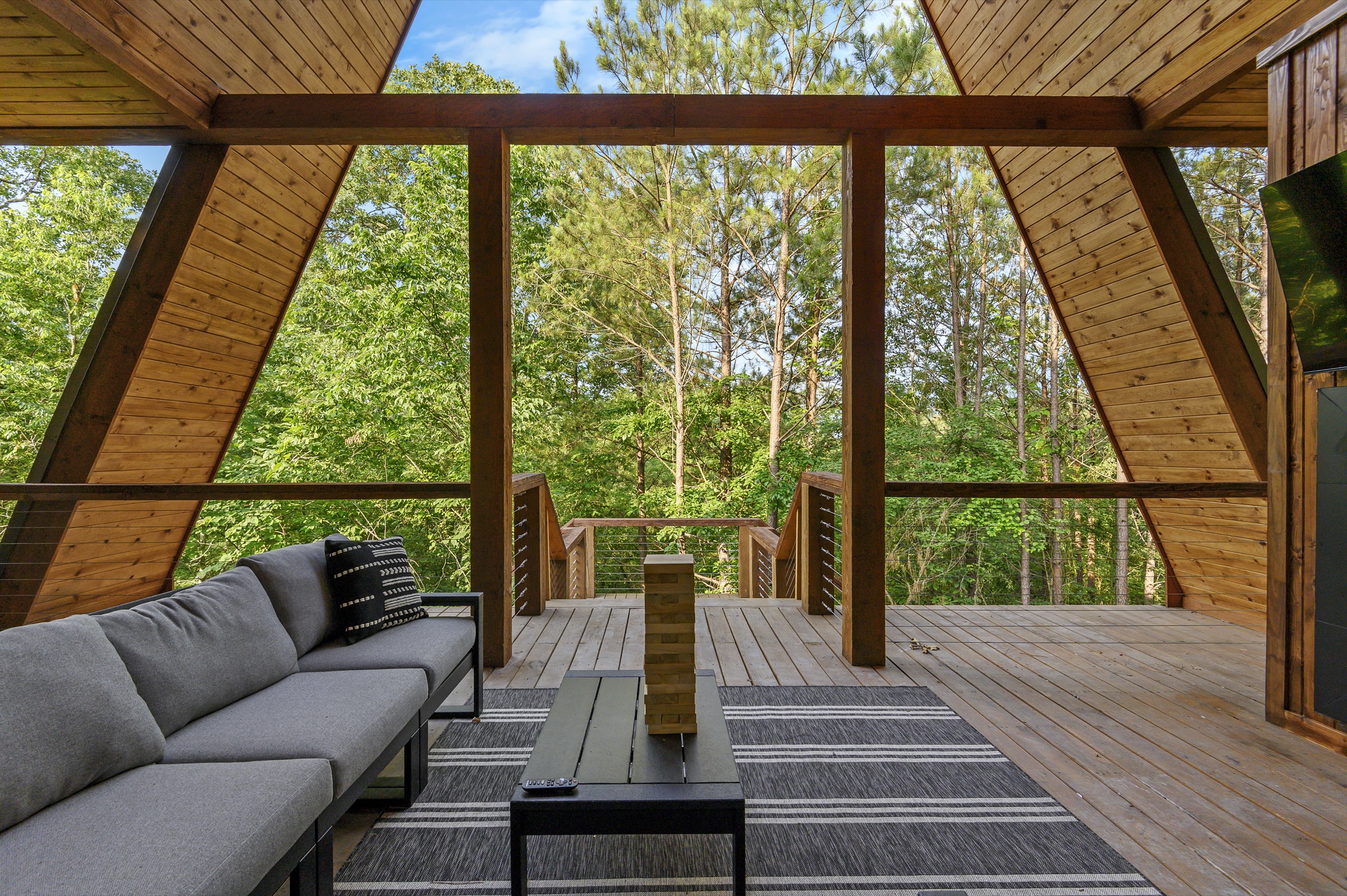 Covered A-frame deck with a sectional and treetop forest views at Moonlight Peak
